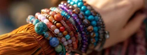 a close-up shot of a woman's wrist adorned with a variety of trendy gemstone bracelets stacked together.