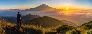 a person standing proudly on top of a mountain peak, basking in the radiant glow of a sunrise.